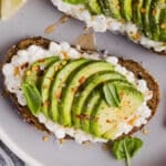 Avocado toast on a plate with hot honey and red pepper flakes.