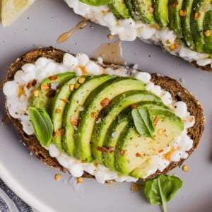Avocado toast on a plate with hot honey and red pepper flakes.