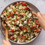 A high protein bean salad with edamame, beans, feta and veggies being mixed.