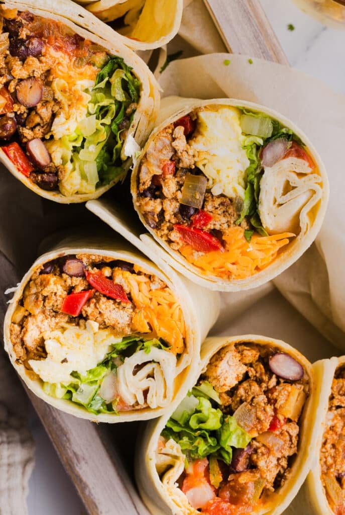 A close up shot of high protein breakfast burritos sliced in half.