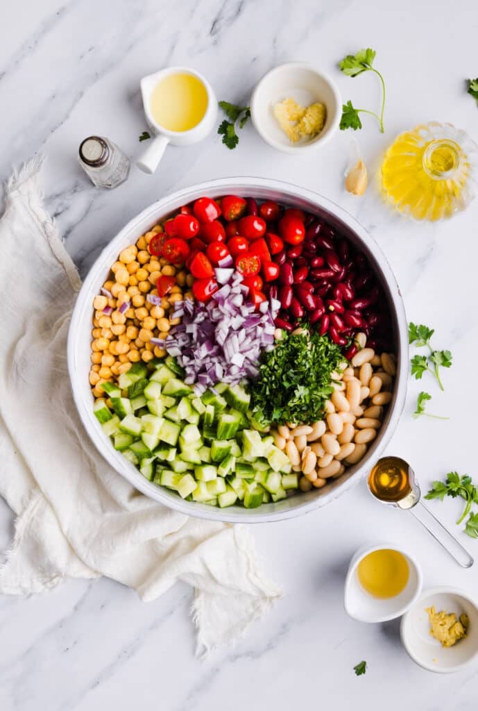 Italian bean salad ingredients in a bowl about to be mixed.