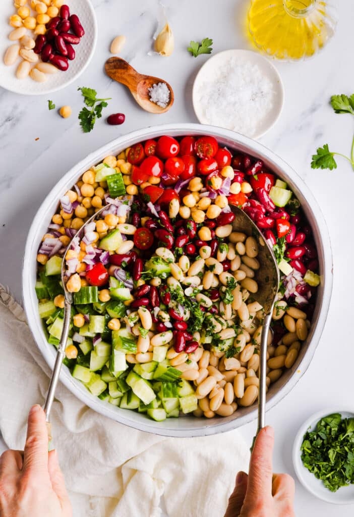Italian bean salad being mixed in a large bowl.