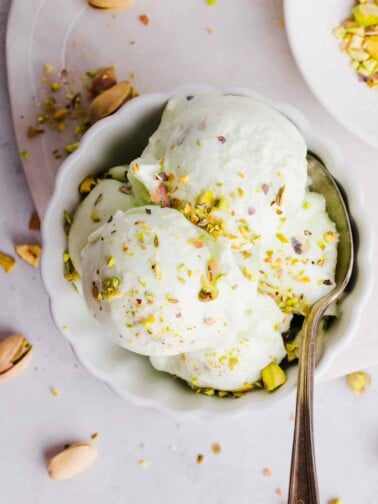 Ninja Creami pistachio ice cream in a bowl with pistachios sprinkled on top and a spoon.