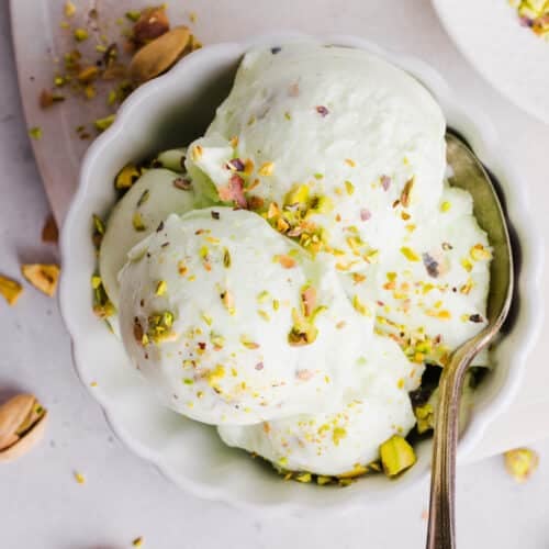 Ninja Creami pistachio ice cream in a bowl with pistachios sprinkled on top and a spoon.