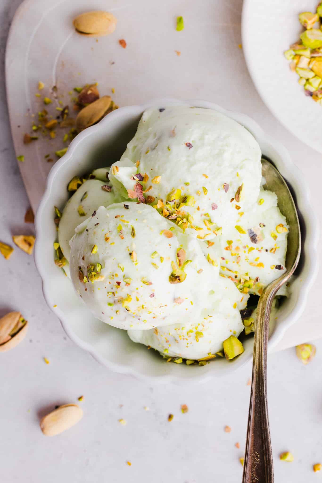 Ninja Creami pistachio ice cream in a bowl with pistachios sprinkled on top and a spoon.