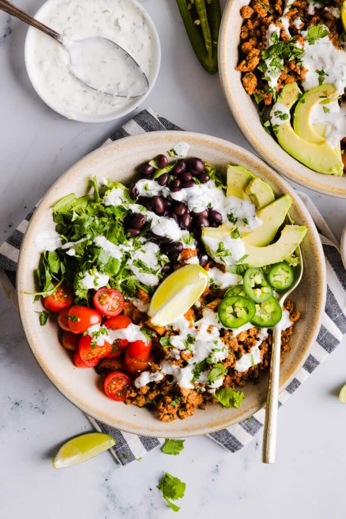 Sweet potato taco bowls assembled with garlic yogurt sauce on top.