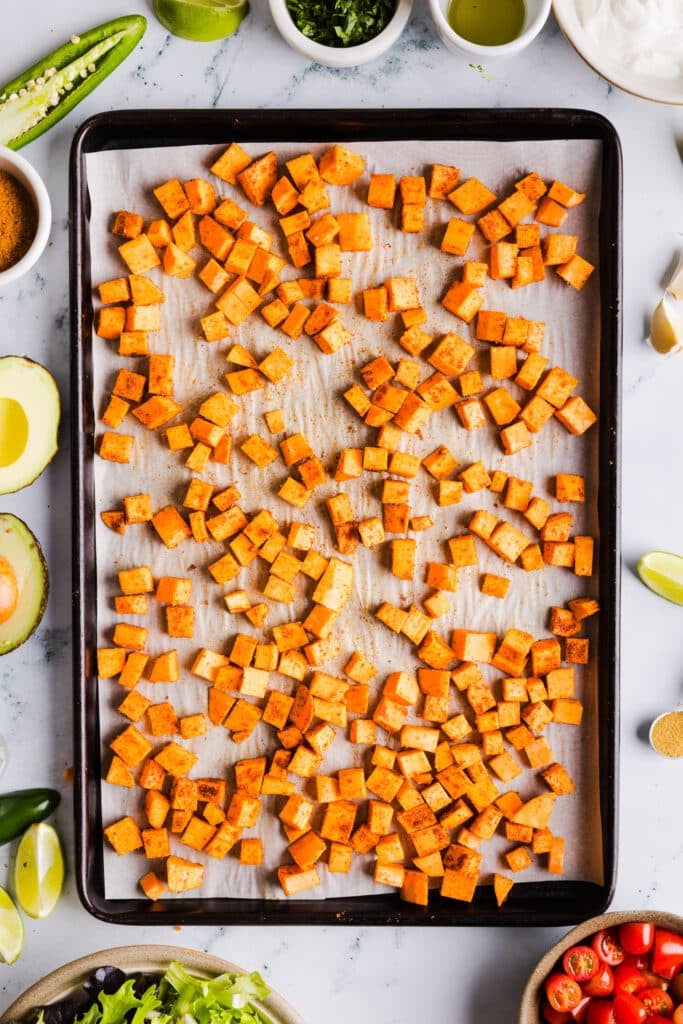Seasoned sweet potatoes on a baking sheet.