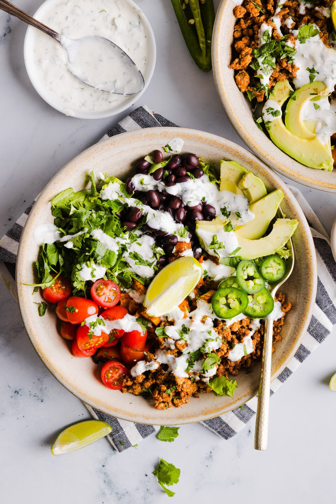Sweet potato taco bowls assembled with garlic yogurt sauce on top.