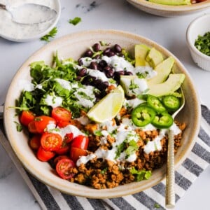 A sweet potato taco bowl assembled with garlic yogurt dressing on top.