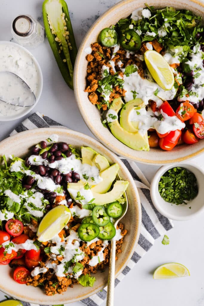 Sweet potato taco bowls assembled with garlic yogurt dressing on top.