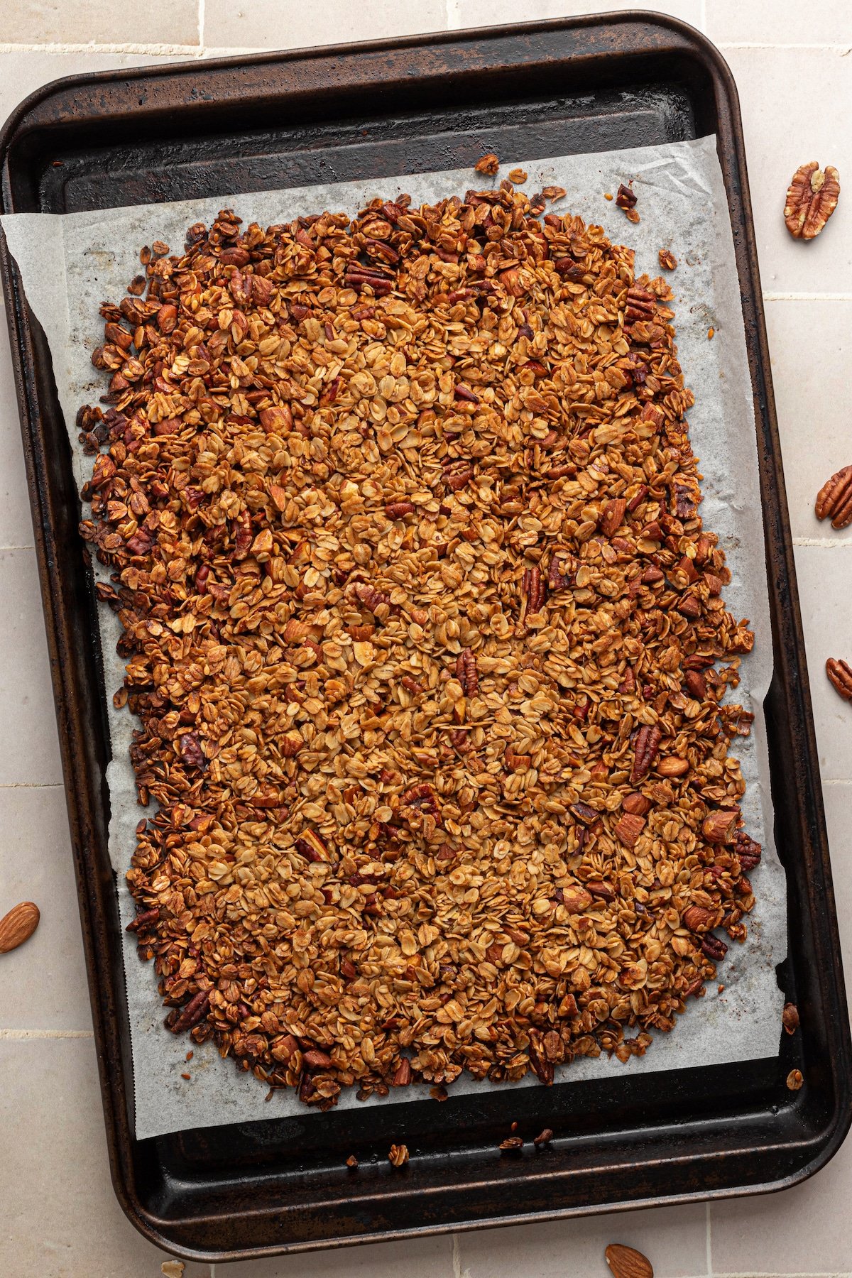 Vanilla nut granola baked on a baking sheet with parchment paper.