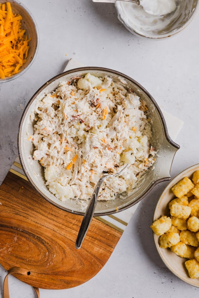 Ingredients for the filling for bacon ranch chicken tater tot casserole mixed in a large bowl.
