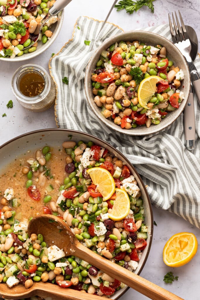 High protein bean salad being served in a small bowl and garnished with lemon.