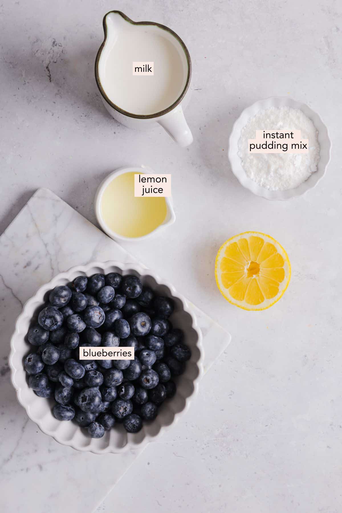 Ingredients for ninja creami blueberry ice cream on a countertop with labels.