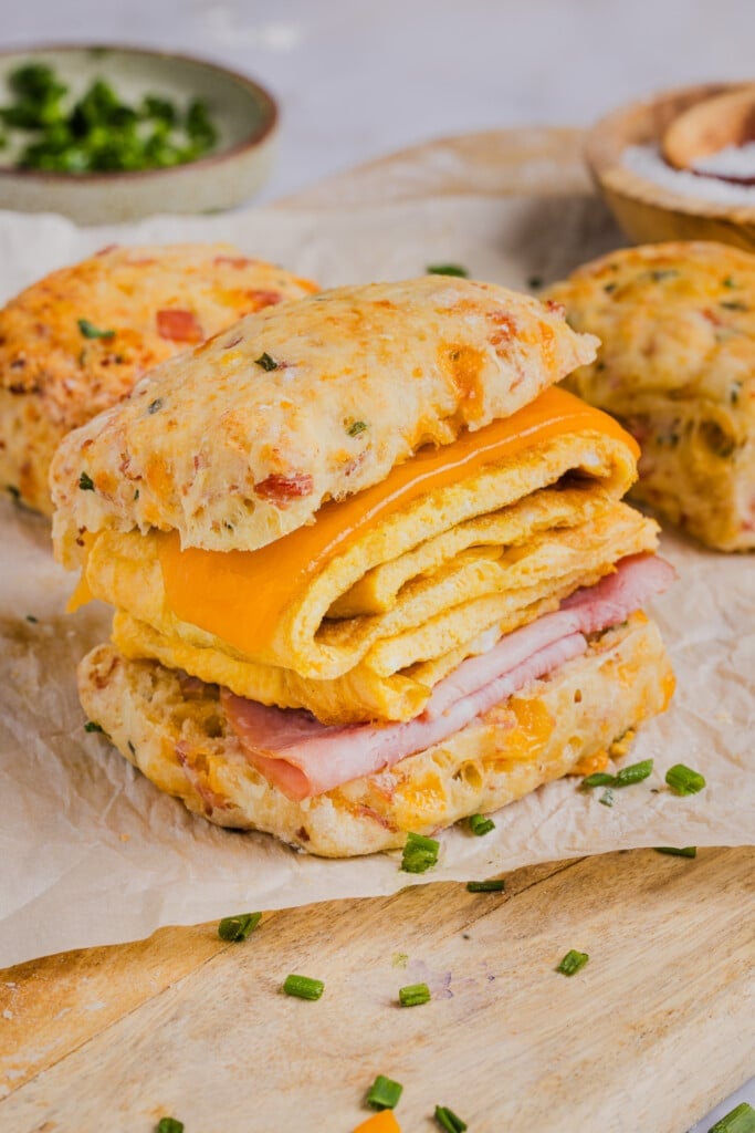 A protein biscuit sliced in half for a breakfast sandwich with ham, egg and cheese.