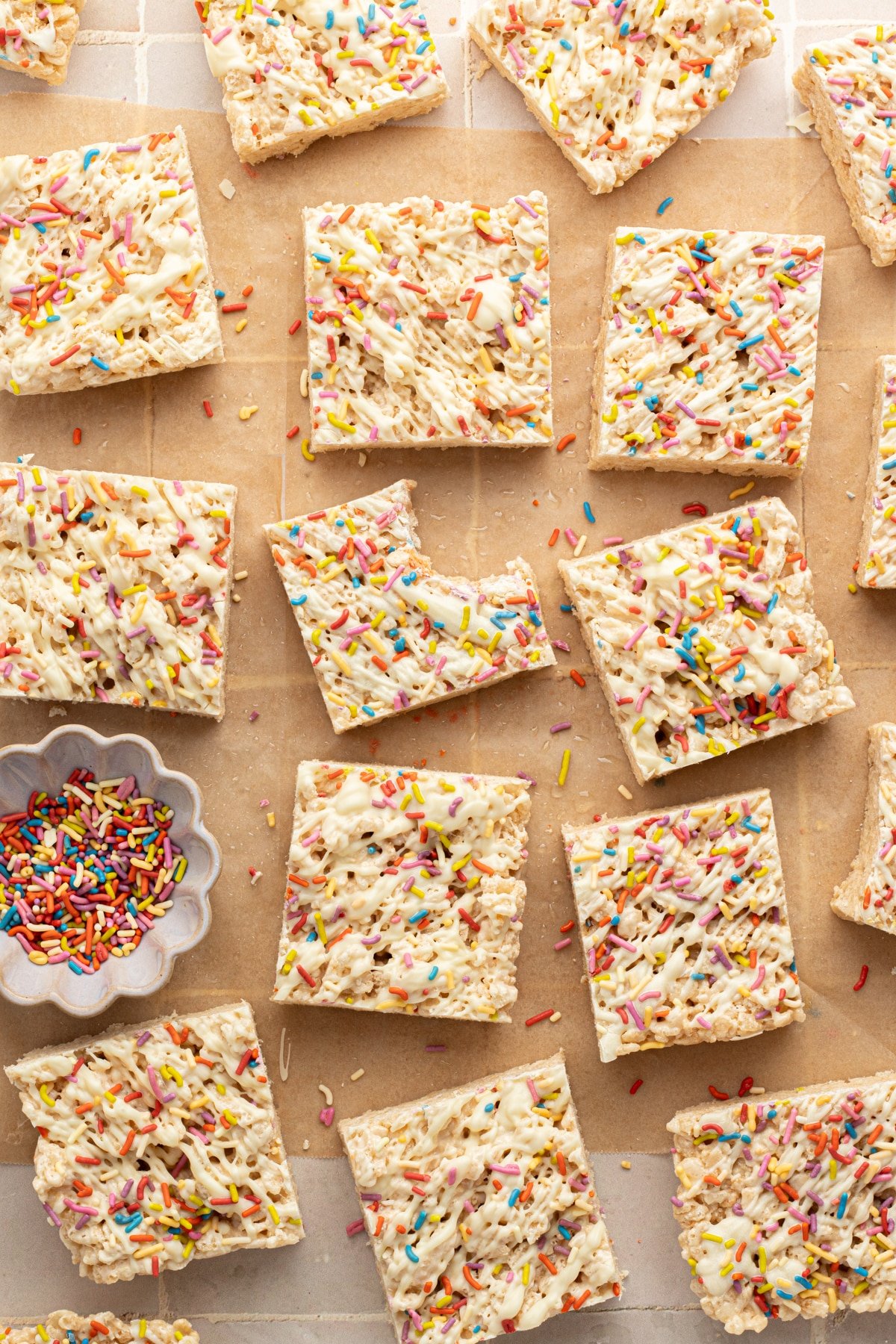 Protein Rice Krispie treats with white chocolate and sprinkles on parchment paper.