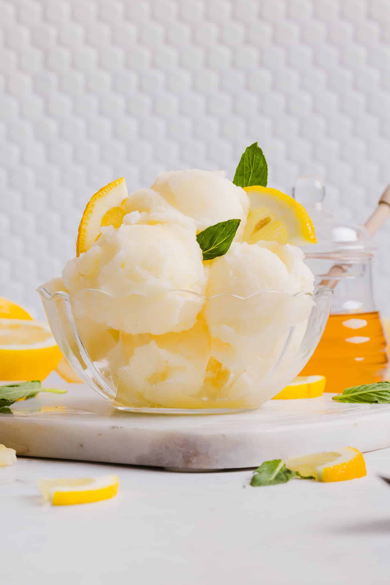 Cool off this summer with this easy Ninja Creami Sorbet Recipe! Bursting with real lemon flavor and sweetened with honey, it's a dream! Several scoops of Ninja Creami lemon sorbet in a bowl.