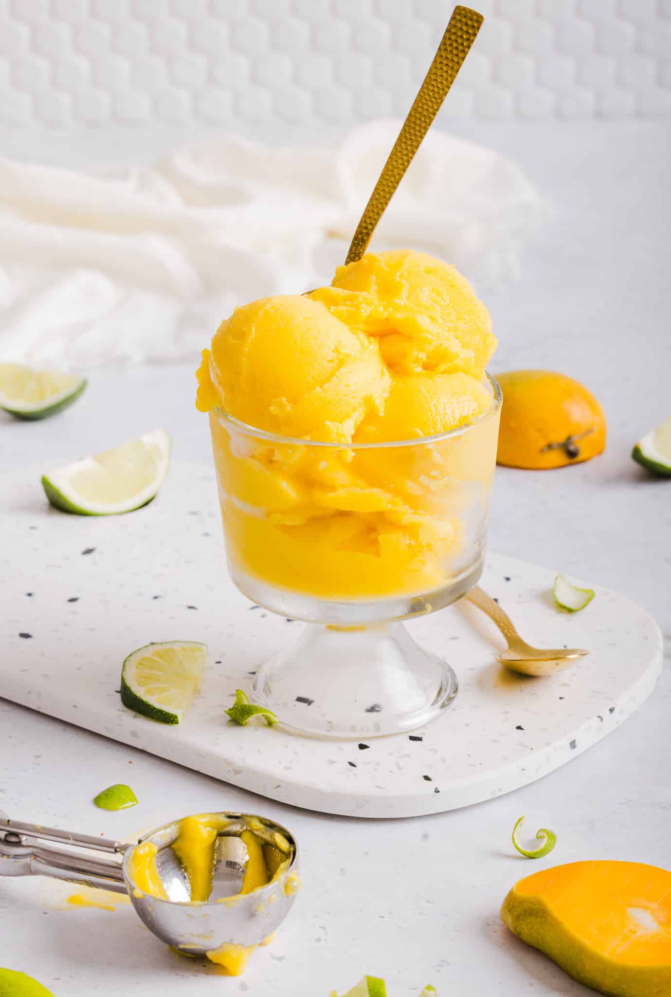 Scoops of Ninja Creami mango sorbet served in a glass dish with a spoon.