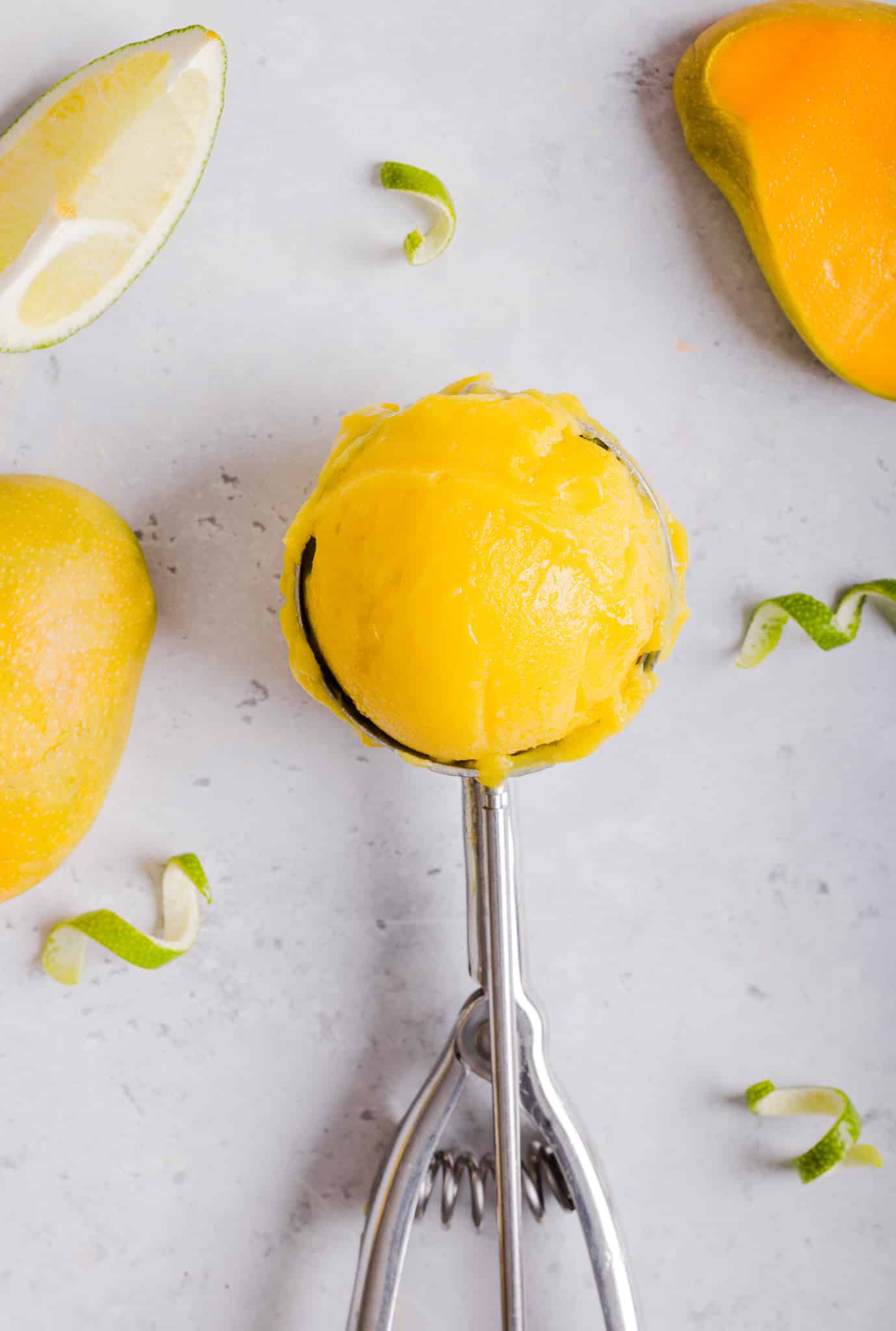 A scoop of Ninja Creami mango sorbet in an ice cream scoop.