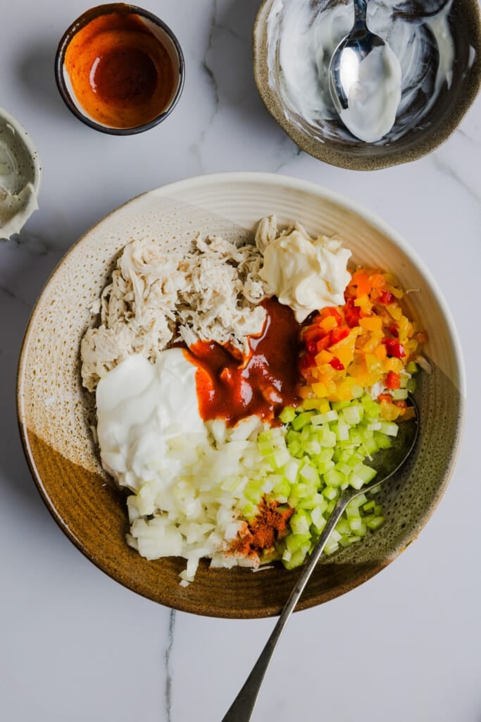 Ingredients for spicy chicken salad are placed in a bowl.
