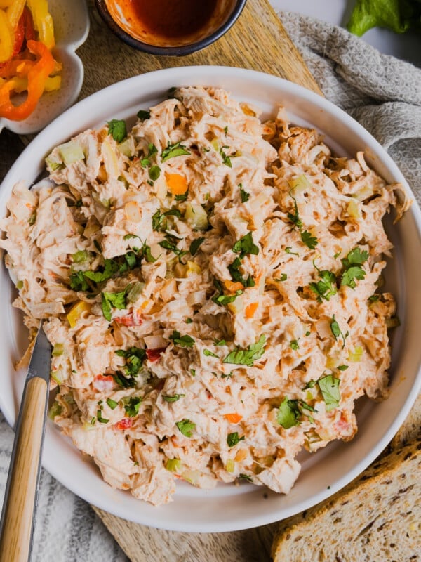 A serving spoon in a bowl of spicy chicken salad.