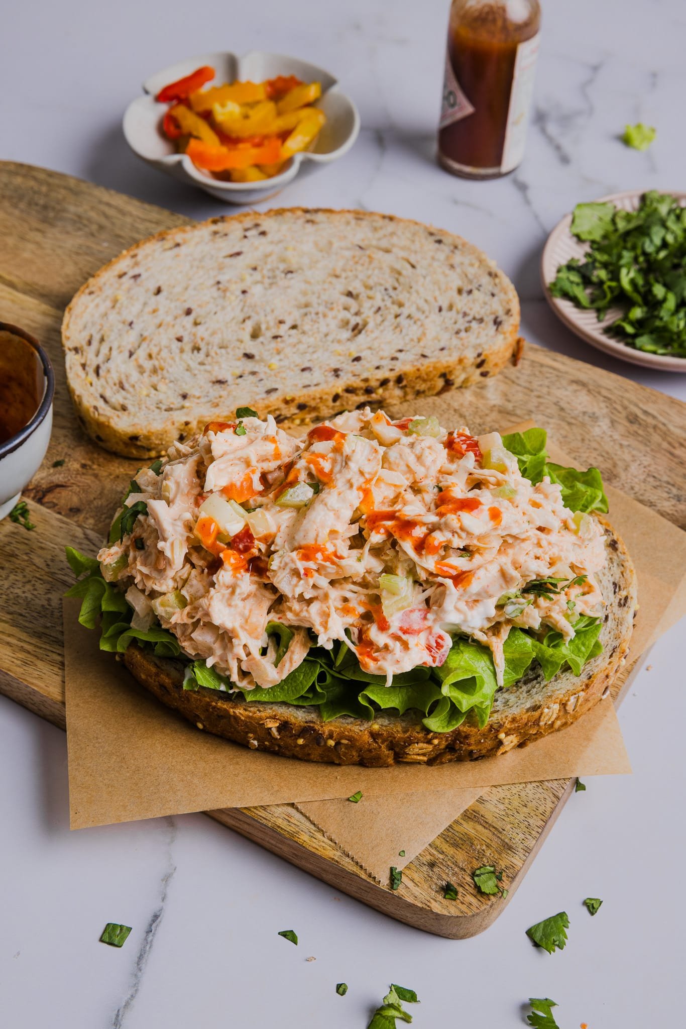 Spicy chicken salad is loaded with tender shredded chicken tossed in a creamy Greek yogurt dressing spiked with hot sauce. Spicy chicken salad is added to bread and lettuce to make a sandwich.