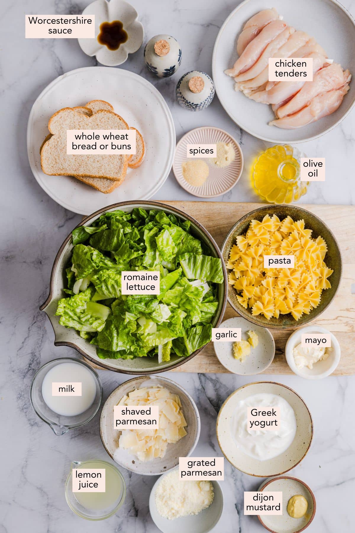 Ingredients for chicken caesar pasta salad on a countertop with labels.