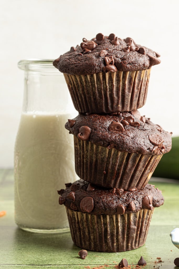 Chocolate veggie muffins stacked with a carafe of milk.