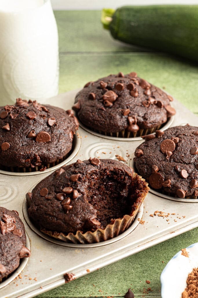 A chocolate veggie muffin in a pan with a bite taken out.
