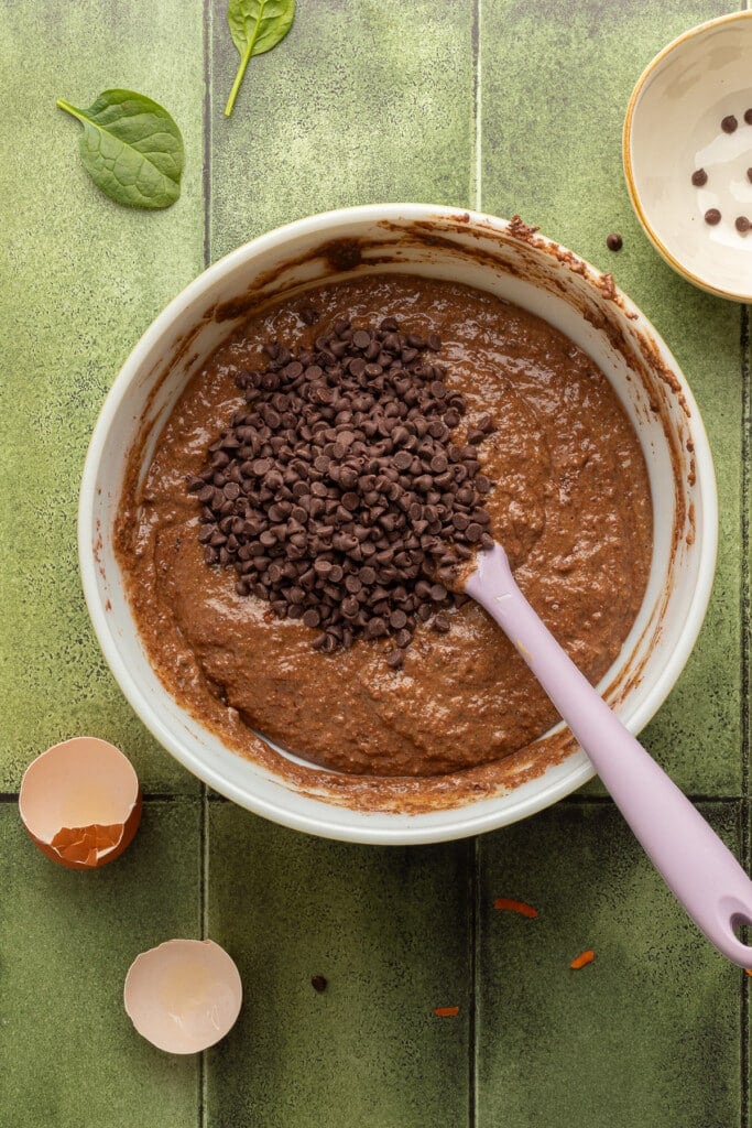 Mini chocolate chips being added to chocolate veggie muffin batter.