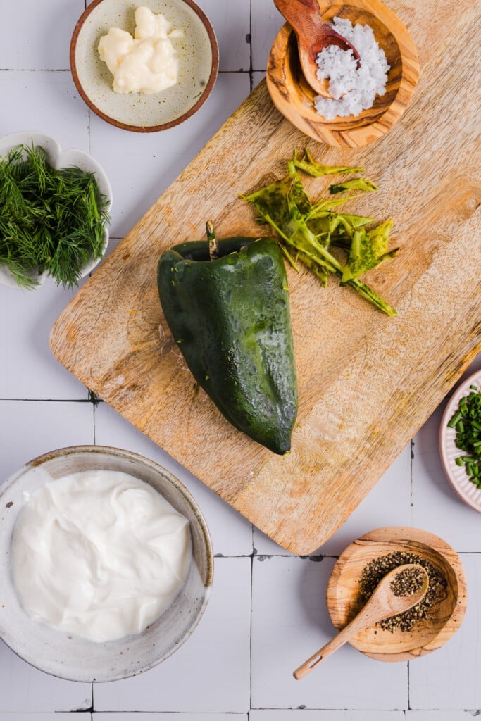 A roasted poblano pepper on a cutting board.