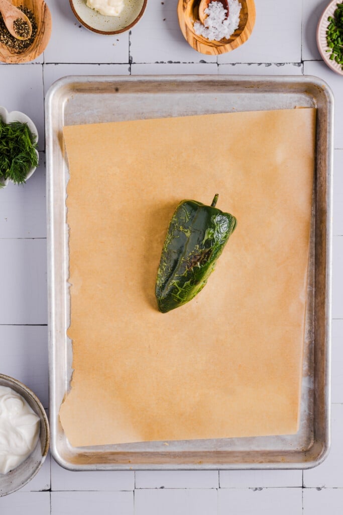 A roasted poblano pepper on parchment paper.