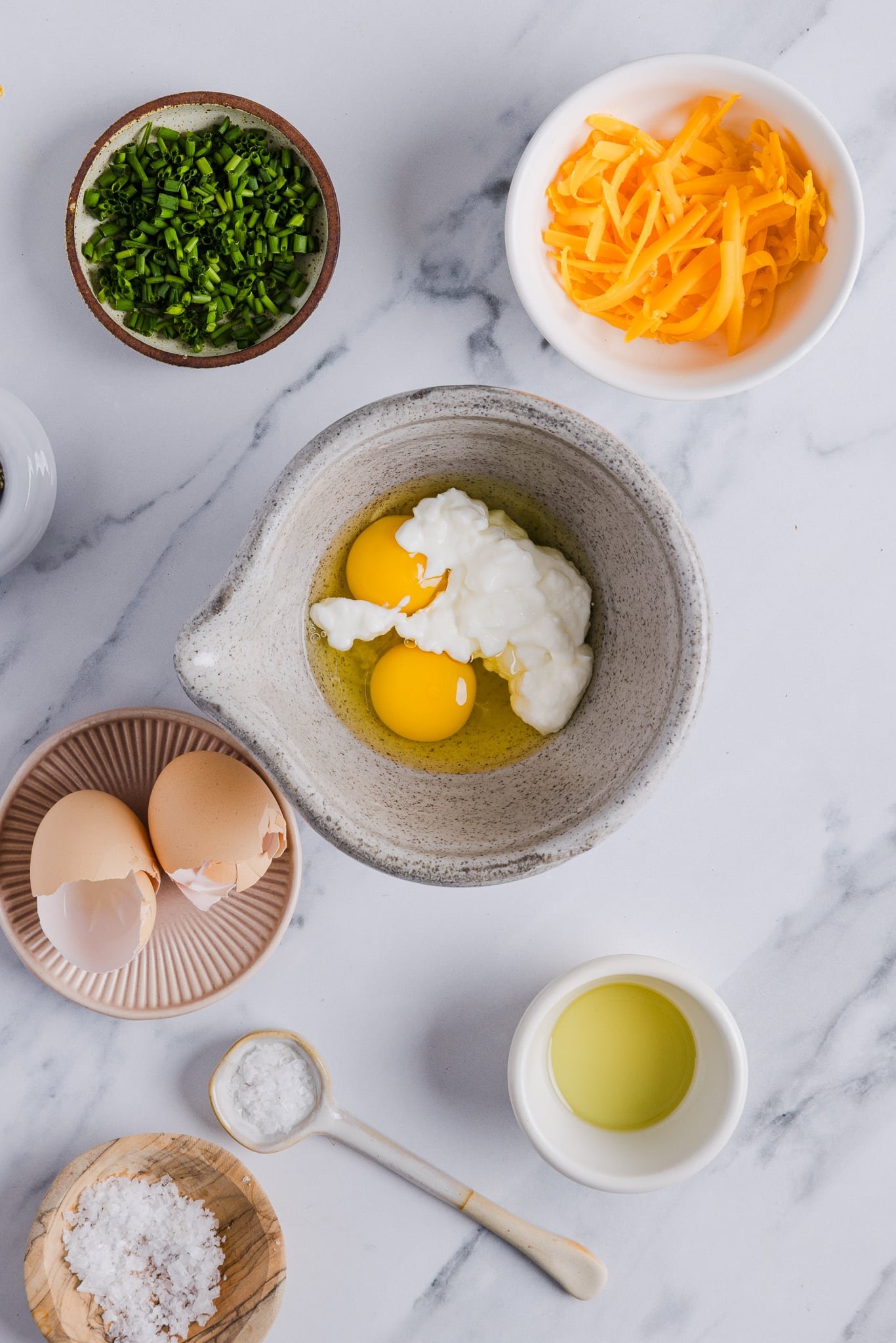 Cottage cheese and eggs being added to a bowl.