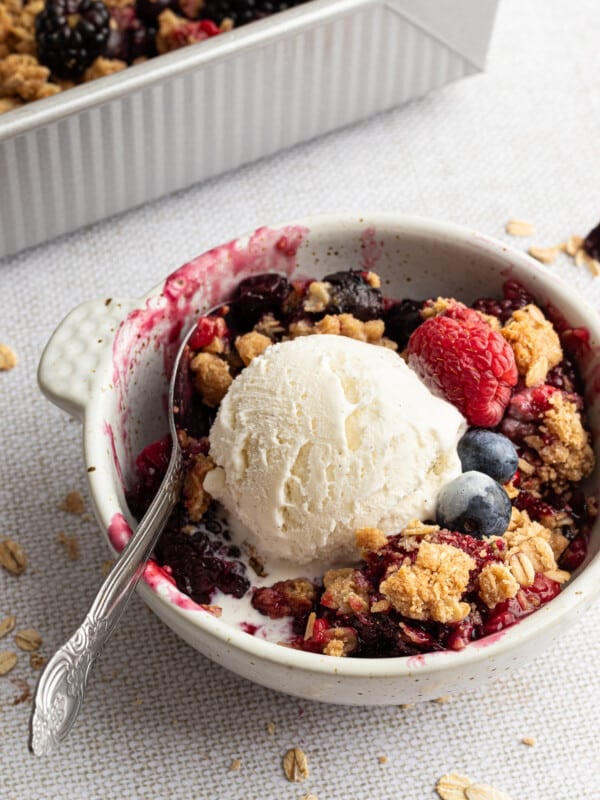A serving of berry crumble topped with a scoop of vanilla ice cream.