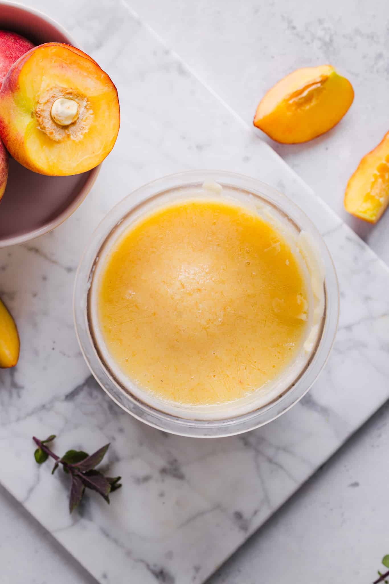 Blended ingredients for peach ice cream frozen in a Ninja Creami pint container.