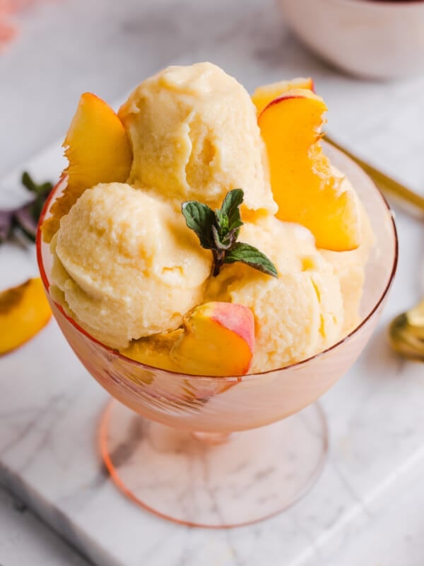 Overhead image of peach ice cream served in a bowl with peach slices.