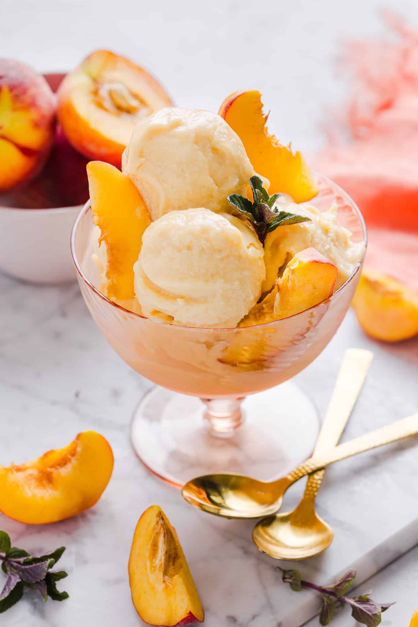 This Ninja Creami Peach Ice Cream is ultra creamy, naturally sweet, and full of juicy peach flavor. It's the perfect low-guilt summer treat. Ninja Creami peach ice cream served in a bowl with peach slices.