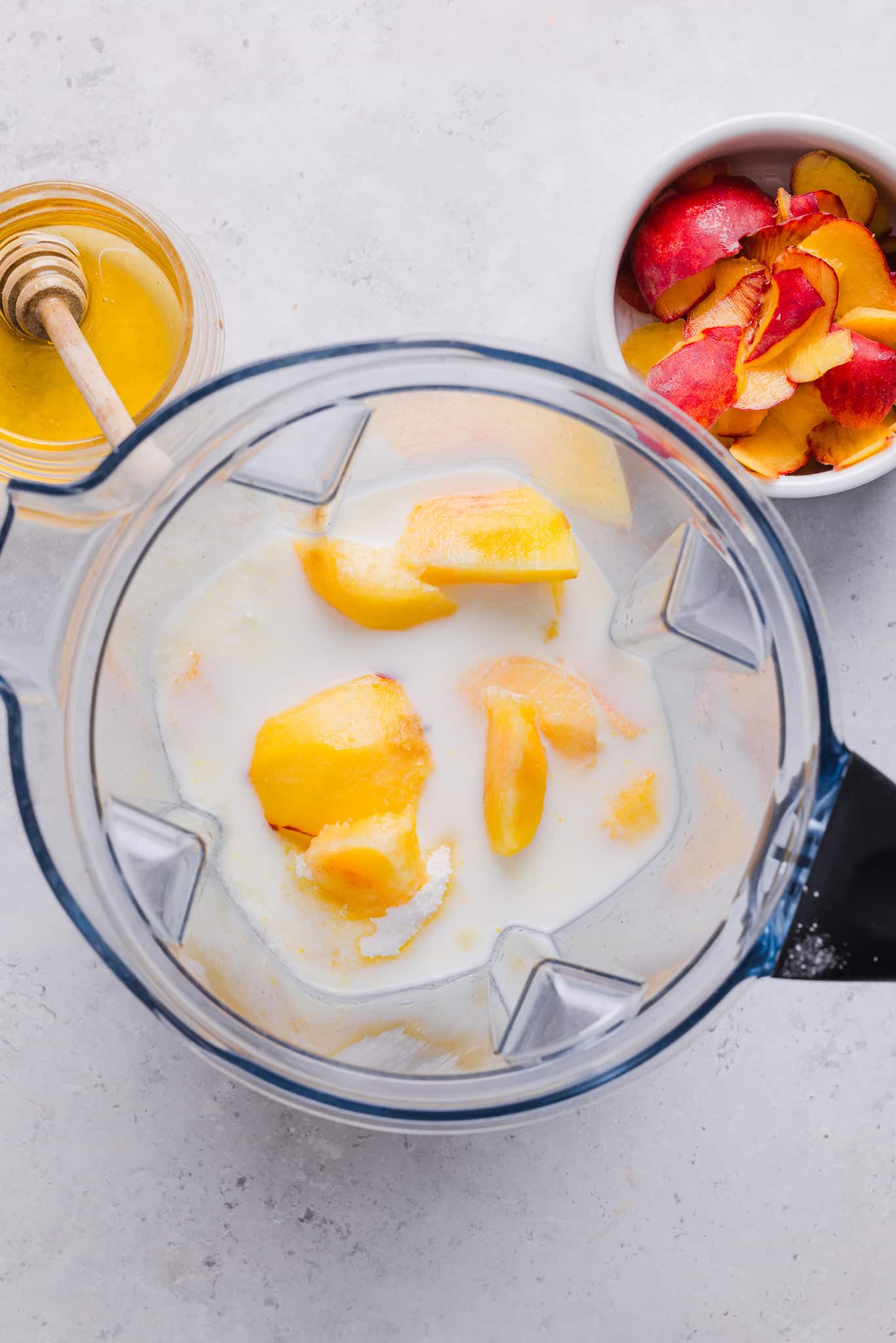 Adding ingredients for Ninja Creami peach ice cream to a blender.
