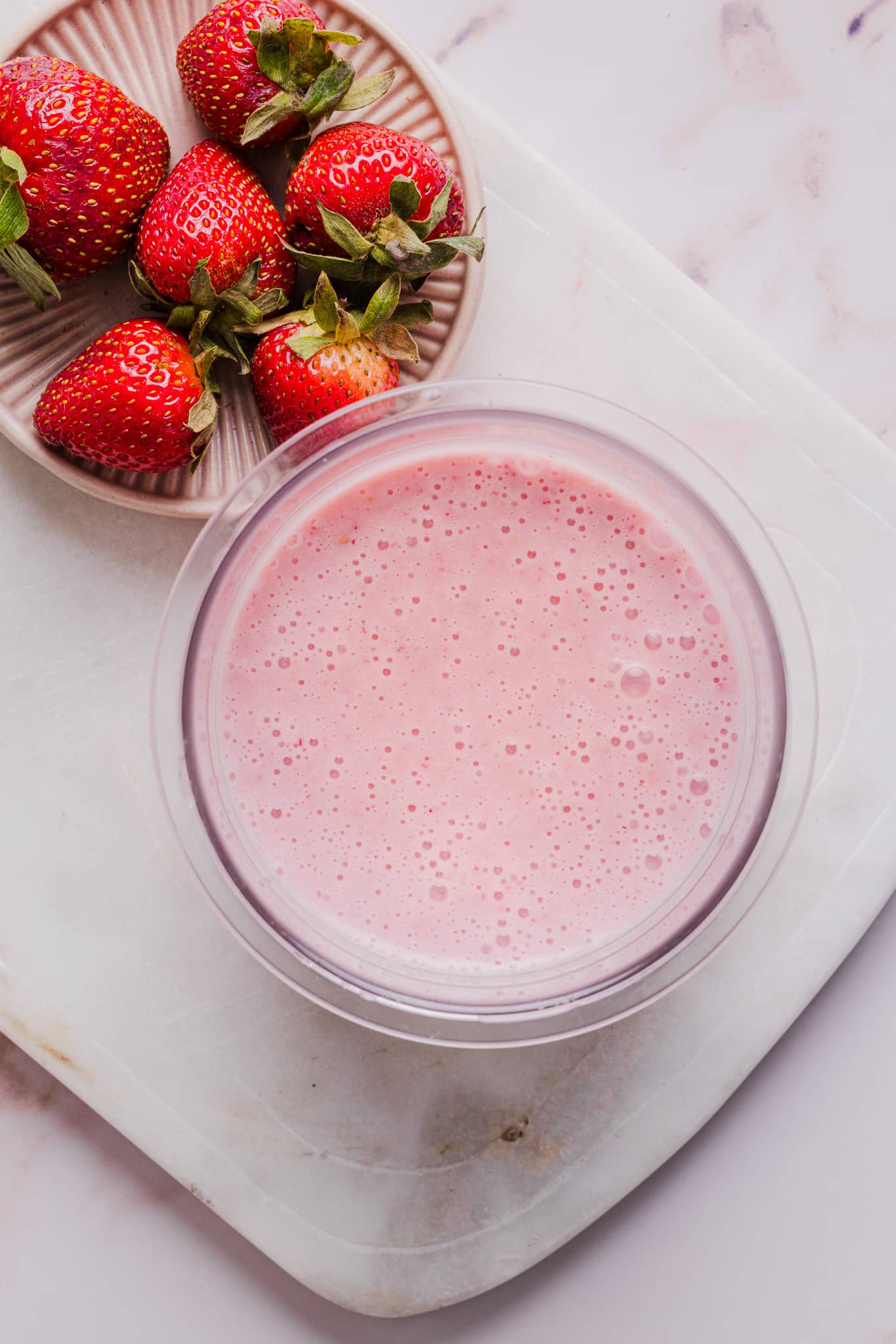 Ingredients for strawberry ice cream blended together in a Ninja Creami pint container.
