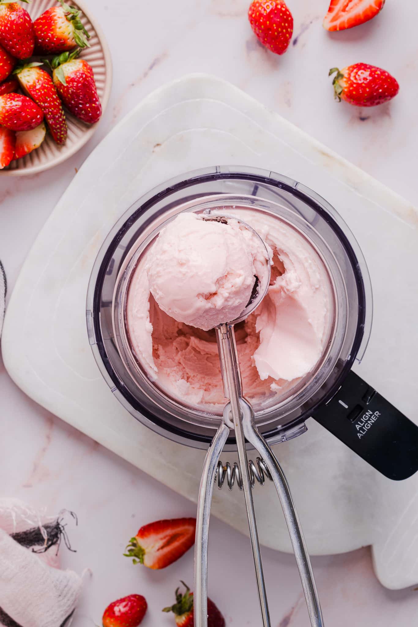 Scooping strawberry ice cream out of a Ninja Creami machine.