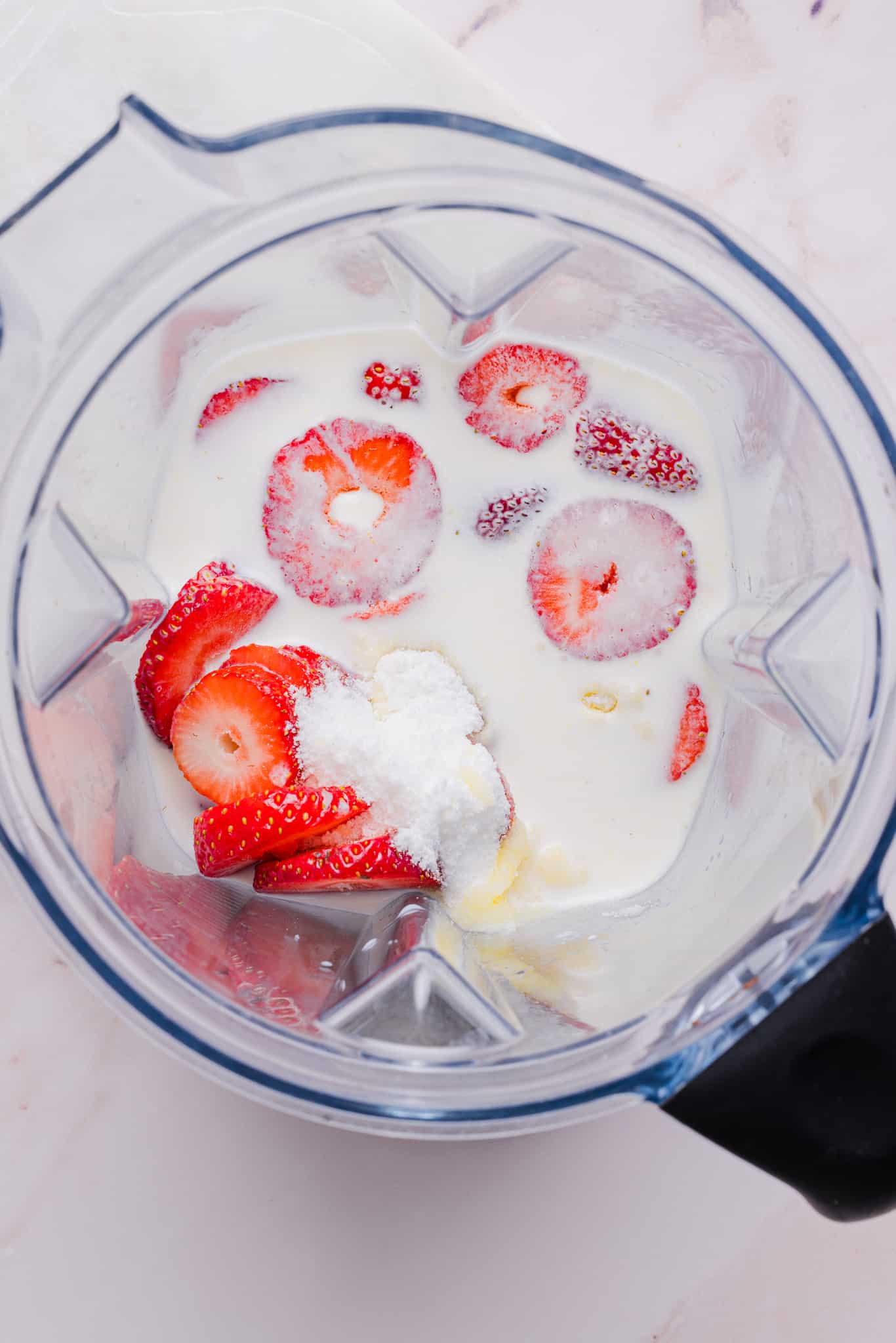Ingredients for strawberry ice cream in a blender.