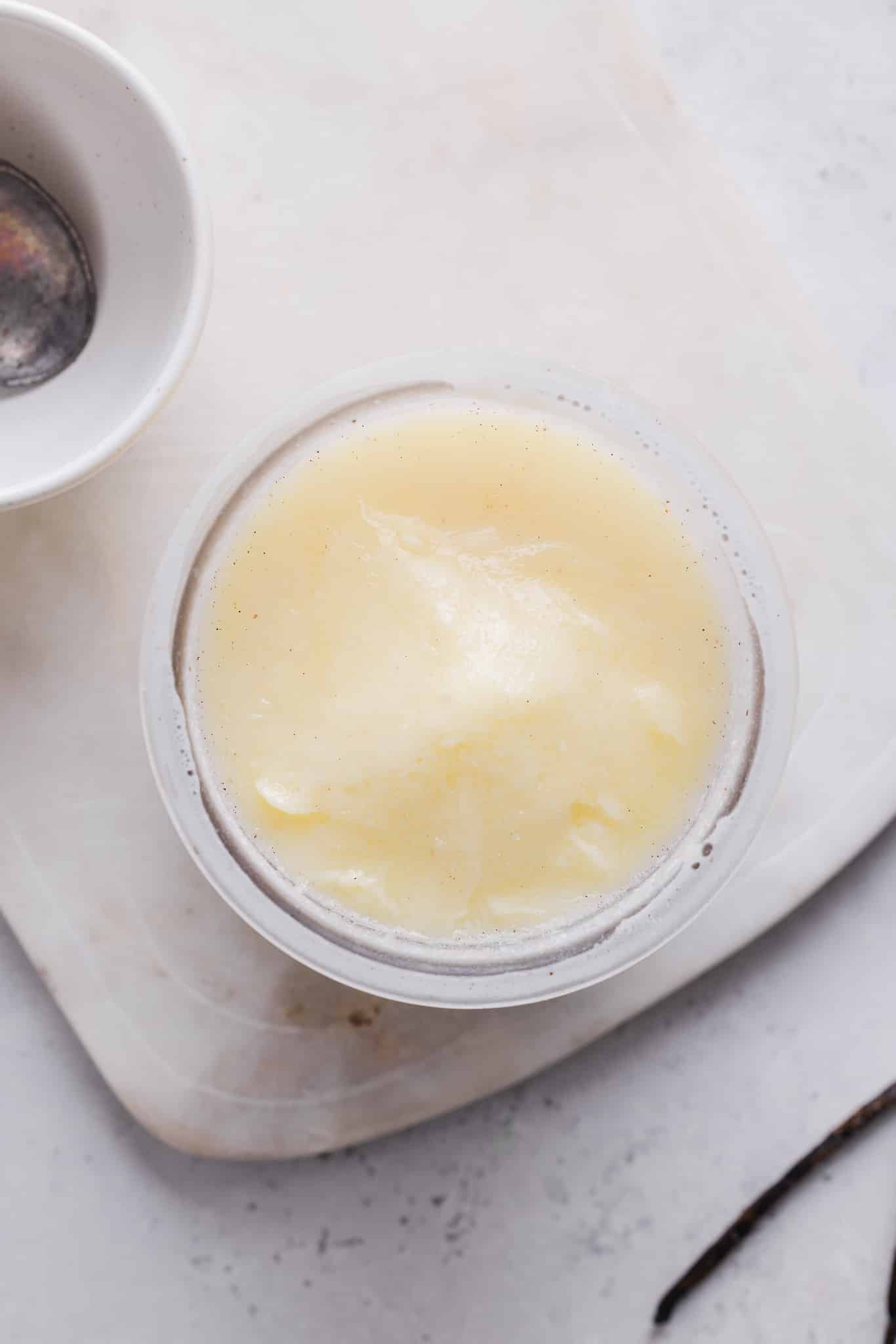 Ingredients for vanilla ice cream frozen in a Ninja Creami pint container.