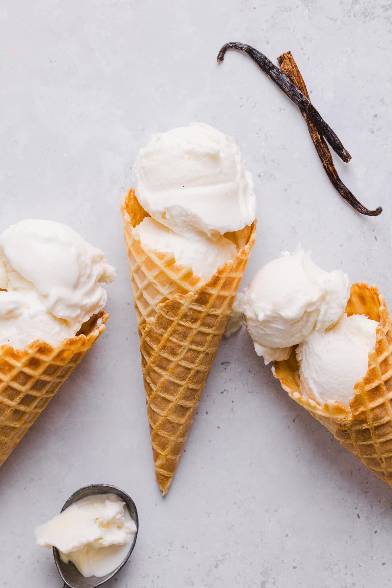 Three ice cream cones loaded with vanilla ice cream.