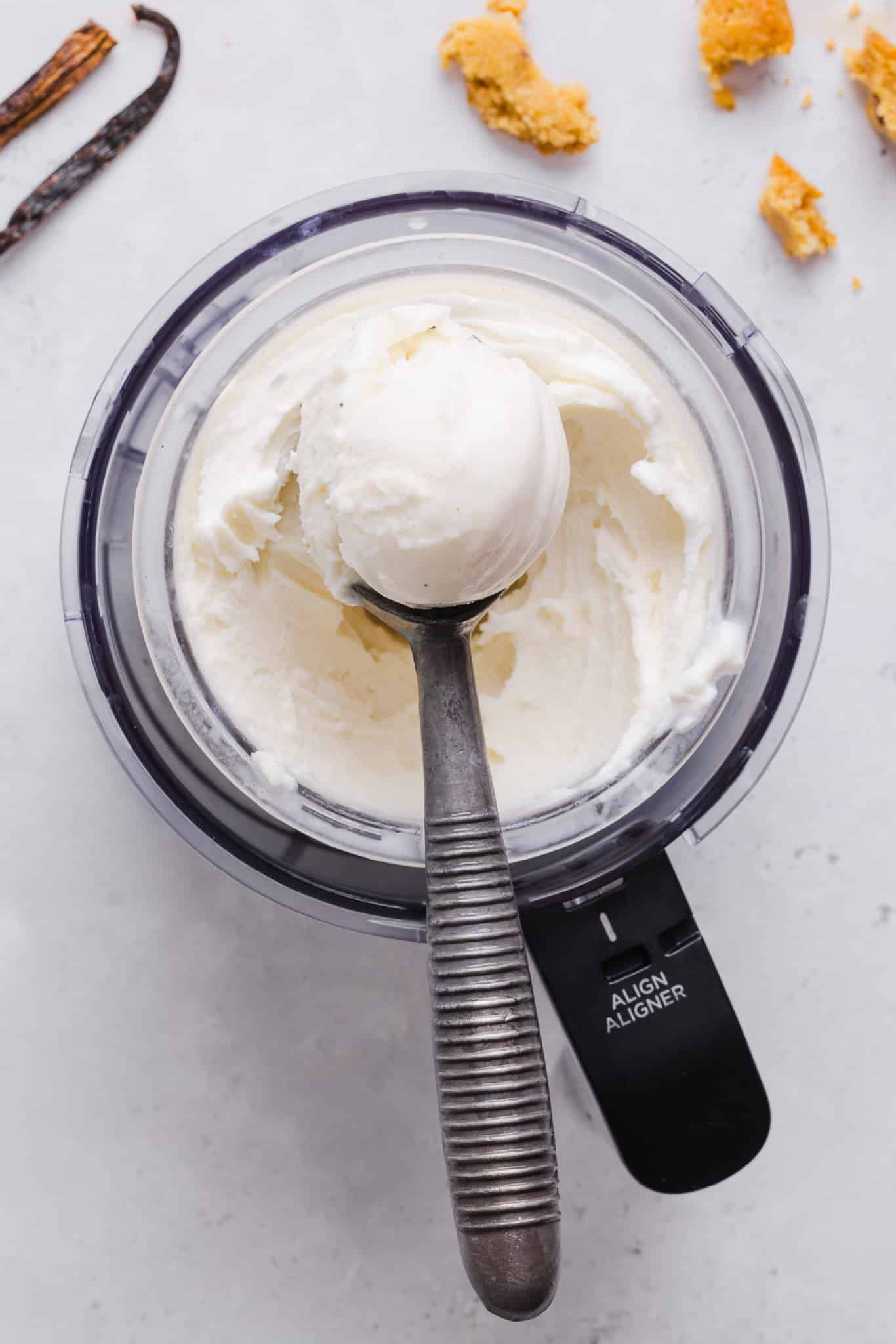 Scooping vanilla ice cream out of a Ninja Creami machine.