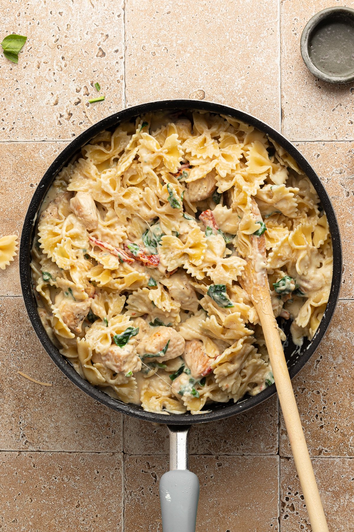 Pasta being added to the marry me chicken pasta in a pan.