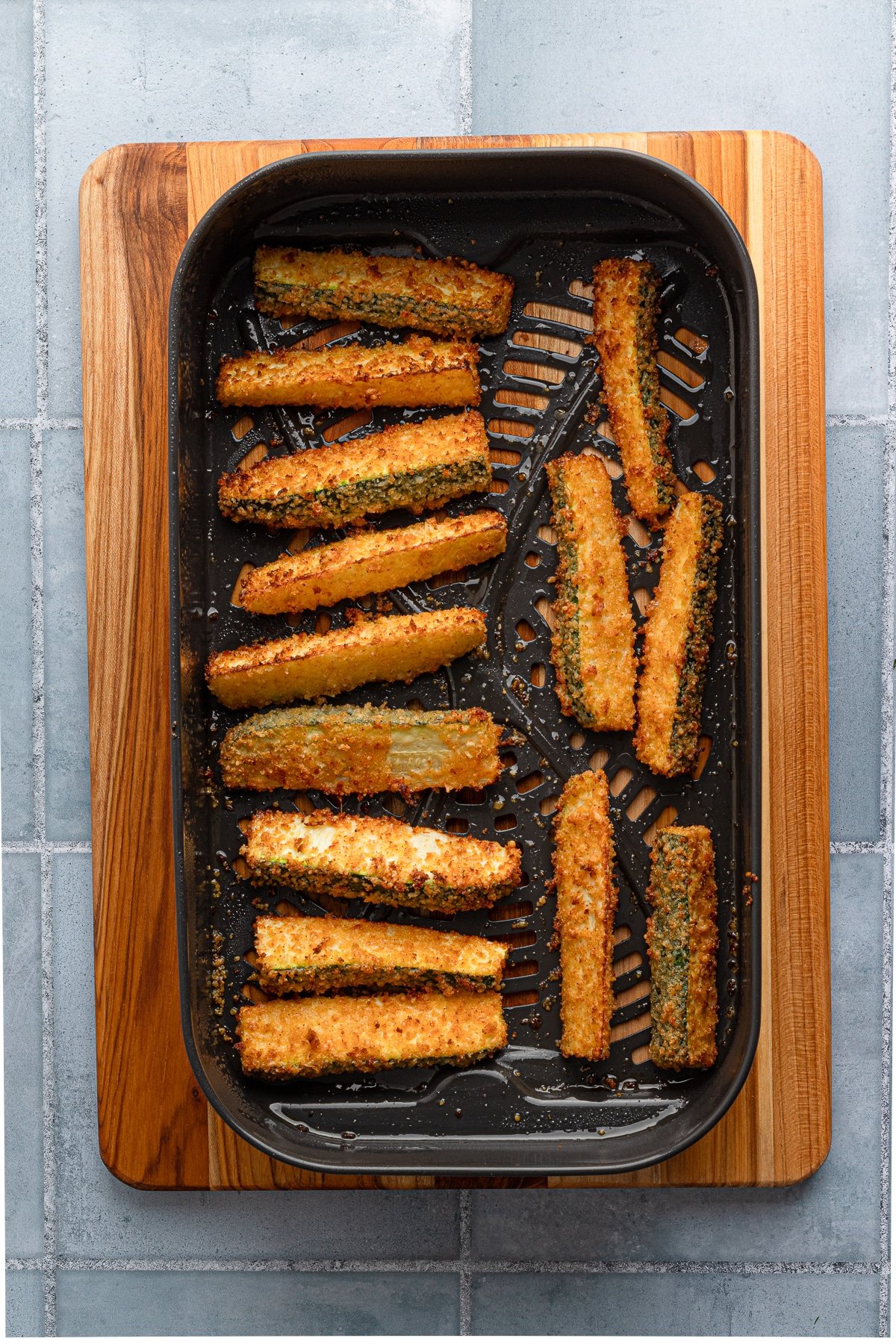 Zucchini fries in the basket of an air fryer.
