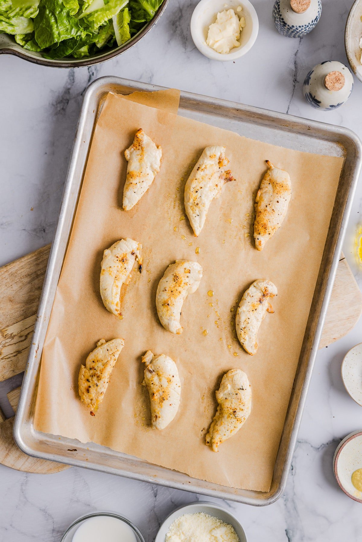 Baked chicken tenders on a sheet pan.