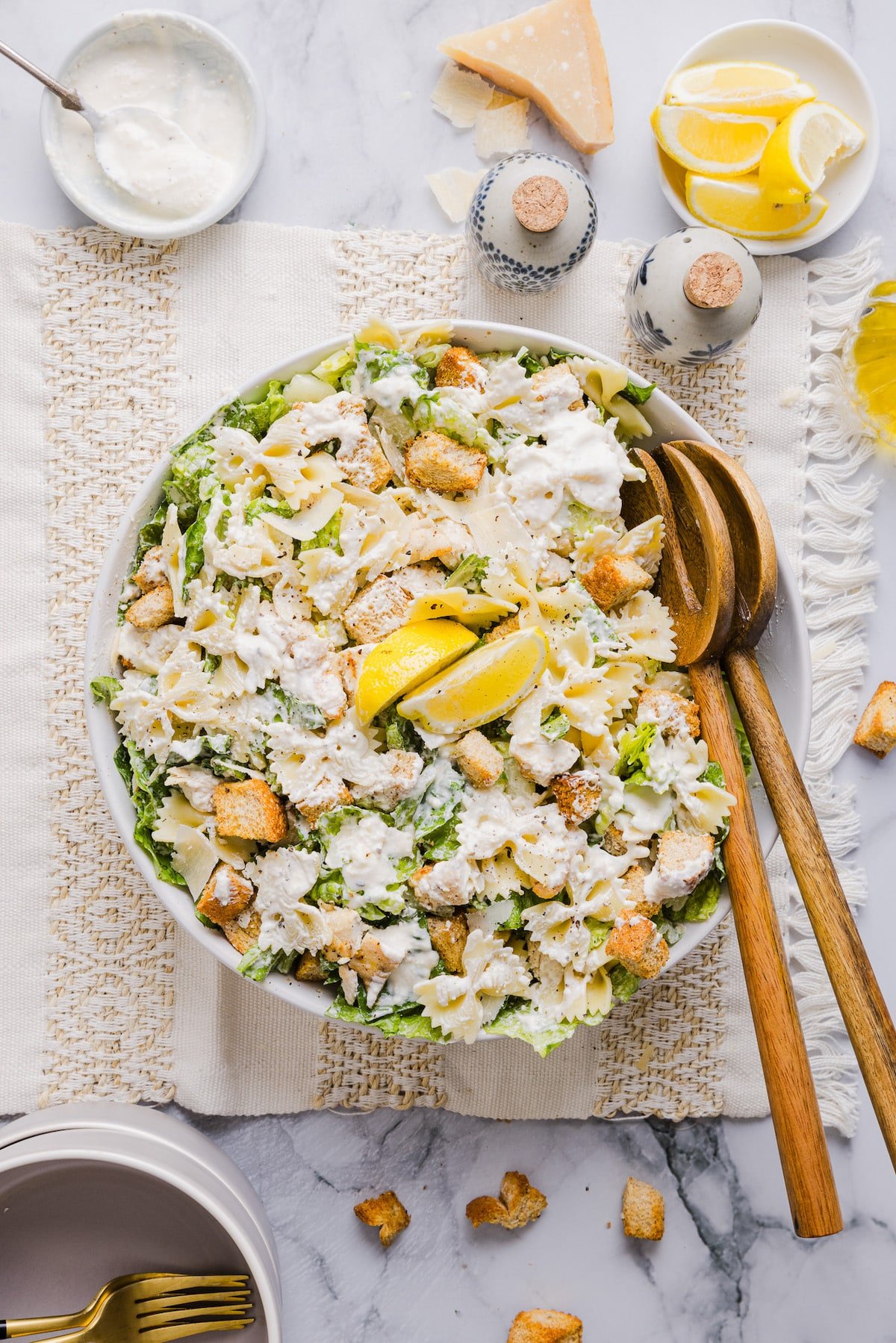 Caesar pasta salad mixed in a large bowl with lemon slices.