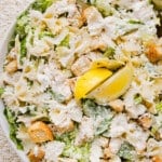 Chicken caesar pasta salad in a large bowl garnished with lemon.
