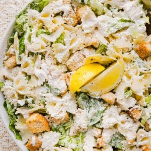 Chicken caesar pasta salad in a large bowl garnished with lemon.